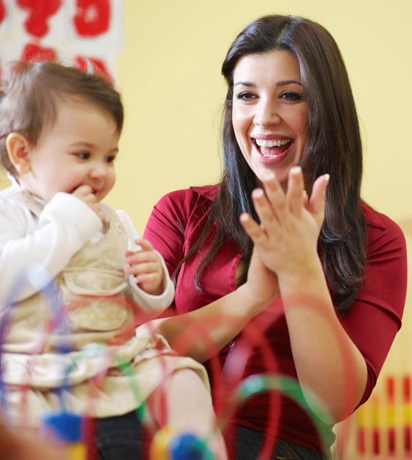 A teacher claps for a toddler she is observing.